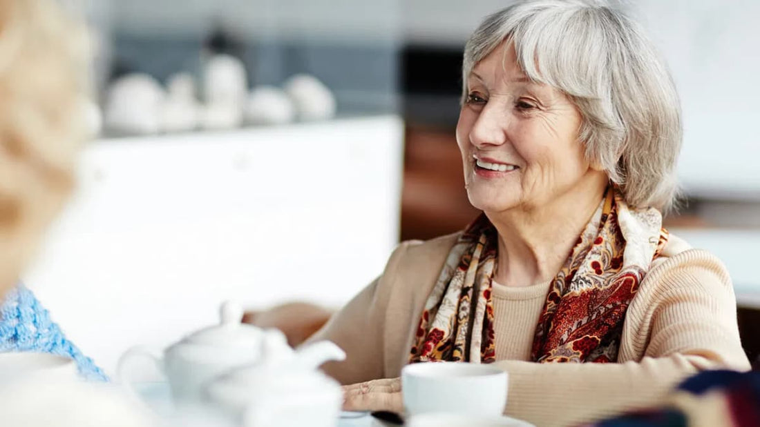 Une femme souriante suit la conversation autour d'un thé