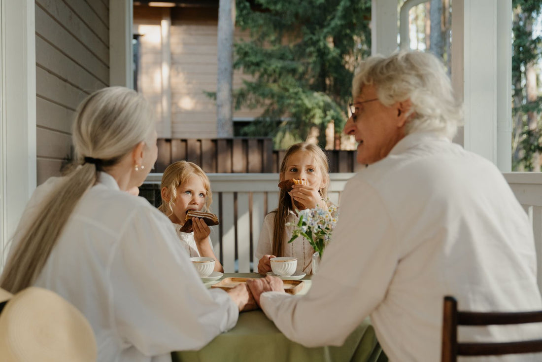 Grands-parents et petites-filles partageant un goûter autour d'une table, sur une terrasse