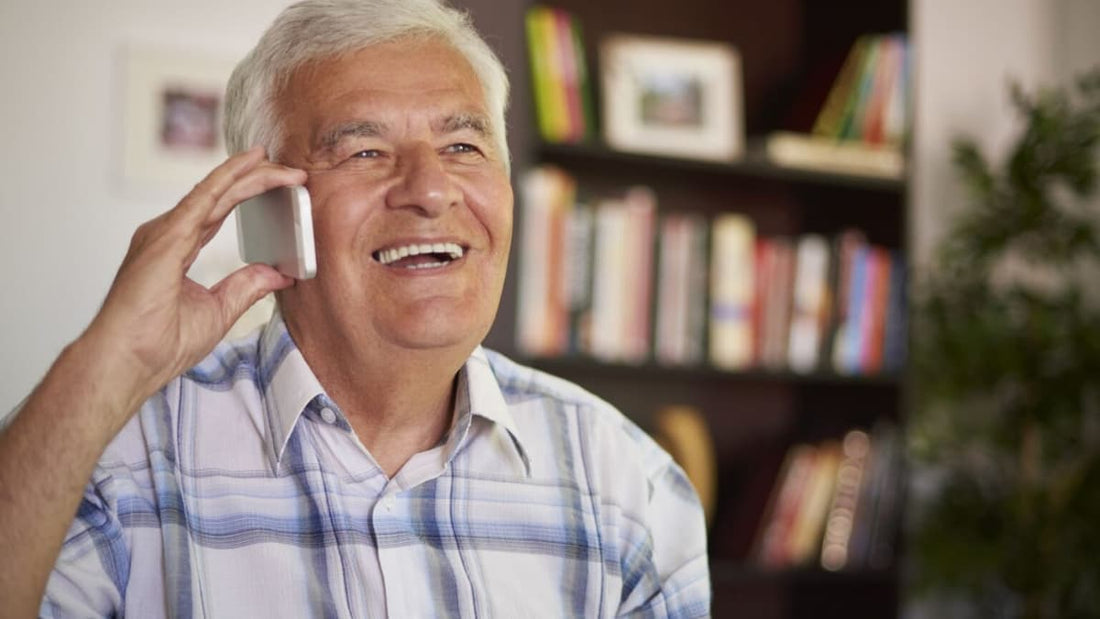 Un senior souriant au téléphone dans son salon